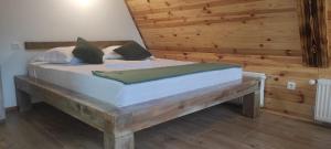 a bed in a room with a wooden wall at Valea cu Dor Verde in Pîrscov