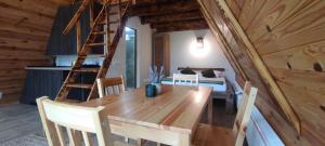 a dining room with a wooden table and a ladder at Valea cu Dor Verde in Pîrscov