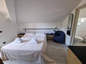 a bedroom with a large white bed and a blue chair at Hotel Garden Bocca di Magra in Bocca di Magra