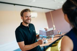 a man is talking to a woman holding a box at MyHotel Steenwijk - Giethoorn in Steenwijk