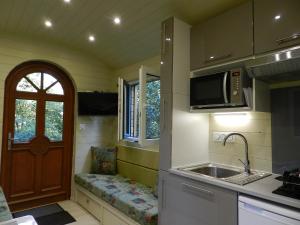 eine kleine Küche mit einer Spüle und einer Mikrowelle in der Unterkunft Gîte Les Marlières in Esquéhéries