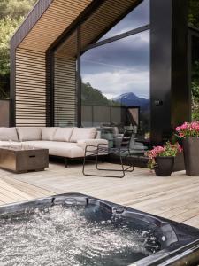 a hot tub on a wooden deck with a couch at Koie Deluxe in Stranda
