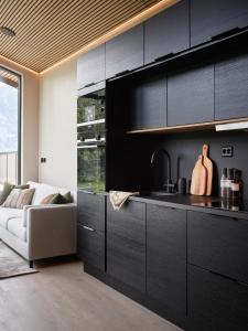 a kitchen with black cabinets and a couch at Koie Deluxe in Stranda