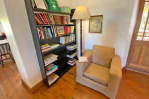 una habitación con una silla y una estantería con libros en The Blue House, en Stanford