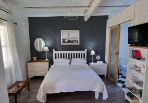 a bedroom with a white bed and a black wall at Rietjiesbos Self Catering in Graaff-Reinet