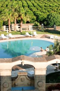 una grande piscina con due persone sedute in essa di Masseria Savoia a Ginosa Marina
