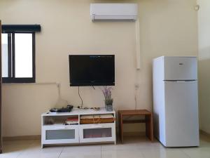 un soggiorno con TV e frigorifero bianco di יחידת דיור עם בריכה פרטית מפנקת a Rosh Pinna