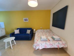 1 dormitorio con 1 cama y 1 sofá azul en יחידת דיור עם בריכה פרטית מפנקת en Rosh Pinna