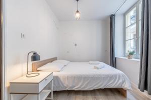 a white bedroom with a bed and a desk at Appartement en centre piétonnier proche de la gare in Thionville