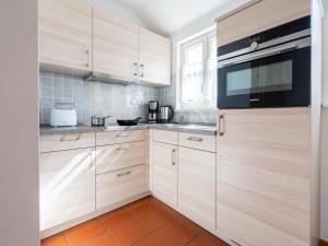 eine Küche mit Holzschränken und einer Mikrowelle in der Unterkunft Feriendorf Rugana - Klassik Appartement mit 1 Schlafzimmer B21 in Dranske + 2 Fotos