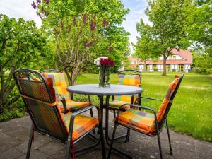 a table with chairs and a vase of flowers at Feriendorf Rugana - Komfort Appartement mit 1 Schlafzimmer und Terrasse B37 in Dranske