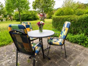 une table et des chaises avec un vase de fleurs dans l'établissement Feriendorf Rugana - Klassik 1-Raum Appartement mit Terrasse B32, à Dranske