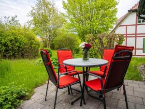 a table with four chairs and a vase of flowers at Feriendorf Rugana - Komfort Appartement mit 1 Schlafzimmer und Terrasse B16 in Dranske