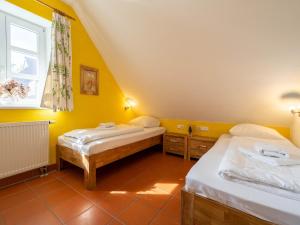 2 Betten in einem Zimmer mit gelben Wänden und einem Fenster in der Unterkunft Feriendorf Rugana - Komfort Appartement mit 2 Schlafzimmern und Terrasse C48 in Dranske