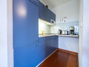 a kitchen with blue cabinets and a tiled floor at Feriendorf Rugana - Klassik Appartement mit 1 Schlafzimmer D16 in Dranske +2 photos