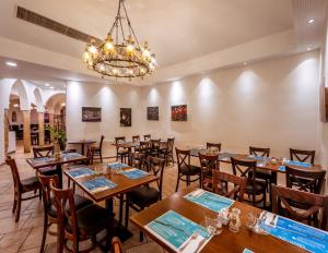 a dining room with tables and chairs and a chandelier at Hagoshrim Hotel & Nature in HaGoshrim