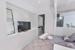 Habitación blanca con cama y TV en THE WHITE HOUSE BEAUSOLEIL- Monaco Border, en Beausoleil
