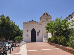 a small white building with a clock tower on a street at Apartamentos Balcón de Maro in Maro