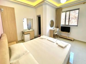 a bedroom with a white bed and a television at The City Gate Hotel in Sarandë
