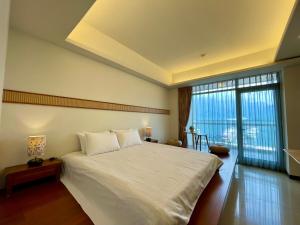 a bedroom with a large white bed and a large window at Ming Hu B&B in Yuchi