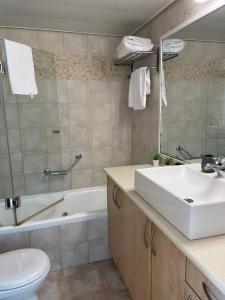 a bathroom with a sink and a toilet and a tub at Oceanus apartment hotel in Herzliya