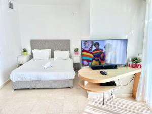 a bedroom with a bed and a desk with a laptop at Oceanus apartment hotel in Herzliya