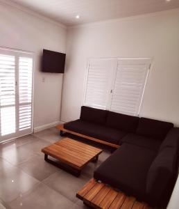 a living room with a black couch and a coffee table at 10 Jock Meiring Guesthouse Unit 2 in Bloemfontein