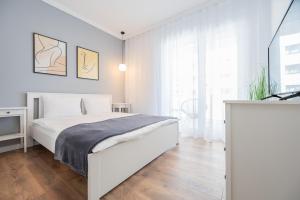 una camera bianca con un letto e una grande finestra di Brioni Flat a Oradea Altre 14 foto