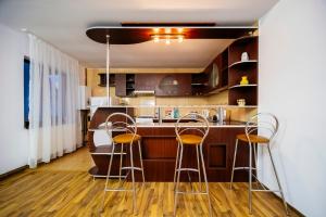 a kitchen with a bar with three stools at Casa Valeria Voronet in Voronet