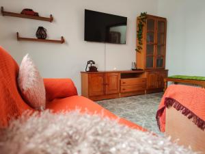 a living room with an orange couch and a tv at Beach View House in Famara