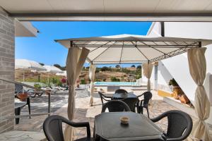 a patio with tables and chairs and an umbrella at Casa dos Jotas in Martinlongo