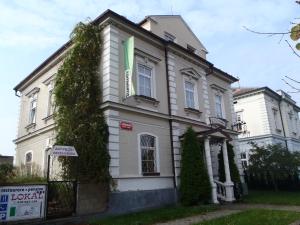 a white house with a green sign in front of it at Pension a restaurace Kůlna in Chomutov