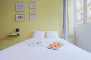 a white bed with a tray of food on it at Apartments WS Opéra-Folies Bergères in Paris