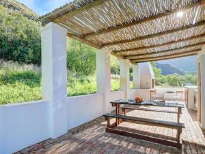 an outdoor patio with a wooden pergola and a table at Varkenskraal Farm in De Rust