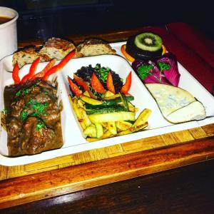 a plate of food with meat and vegetables on a table at Eco Yourte Les Airelles in Saint-Anthème