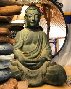 a statue of aitating buddha in front of a mirror at Eco Yourte Les Airelles in Saint-Anthème