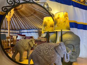 a mirror with a statue of a head and an elephant at Eco Yourte Les Airelles in Saint-Anthème