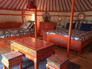 a room with two beds and two tables in a yurt at Eco Yourte Les Airelles in Saint-Anthème