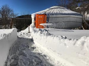 a yard covered in snow with a yurt in the background at Eco Yourte Les Airelles in Saint-Anthème
