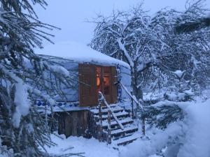 a cabin in the snow with the door open at Eco Yourte Les Airelles in Saint-Anthème