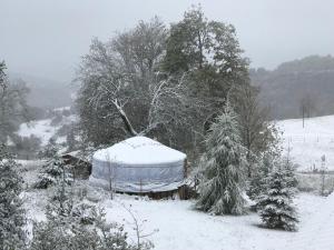 a yurt is covered in snow in a yard at Eco Yourte Les Airelles in Saint-Anthème