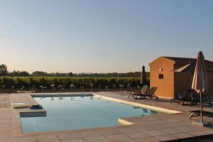 a large swimming pool with chairs and umbrellas next to a building at MARIS APARTMENTS - Airport Shuttle in Alghero