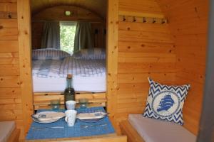 mesa de comedor en una cabaña de madera con cama en Schlaffässer Teichwiesenhof en Oldenburg in Holstein