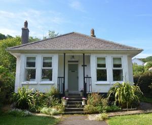 a small white house with a porch and stairs at Oakroyd in Gorran Haven