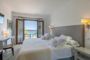 1 dormitorio con 1 cama blanca grande y balcón en Hoposa Bahia, en Puerto Pollensa
