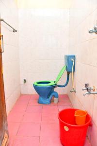 ein Badezimmer mit einem blauen WC und einem roten Eimer in der Unterkunft Lakshmi cottage in Mahabalipuram