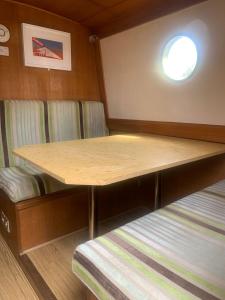 Cette petite chambre comprend une table et un lit. dans l'établissement Narrowboat stay or Moving Holiday Abingdon On Thames DIFFERENT RATES APPLY ENSURE CORRECT RATE SELECTED, à Abingdon