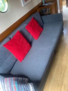 a bed with two red pillows on top of it at Narrowboat stay or Moving Holiday Abingdon On Thames DIFFERENT RATES APPLY ENSURE CORRECT RATE SELECTED in Abingdon