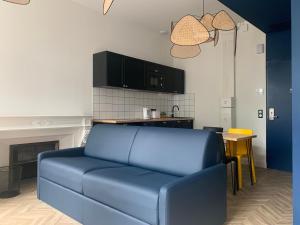 a blue couch in a living room with a kitchen at Pau's Appart - Pau Centre in Pau