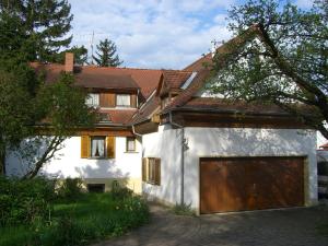 a white house with a wooden garage door at Ferienwohnung Lucia Huber in Uhldingen-Mühlhofen